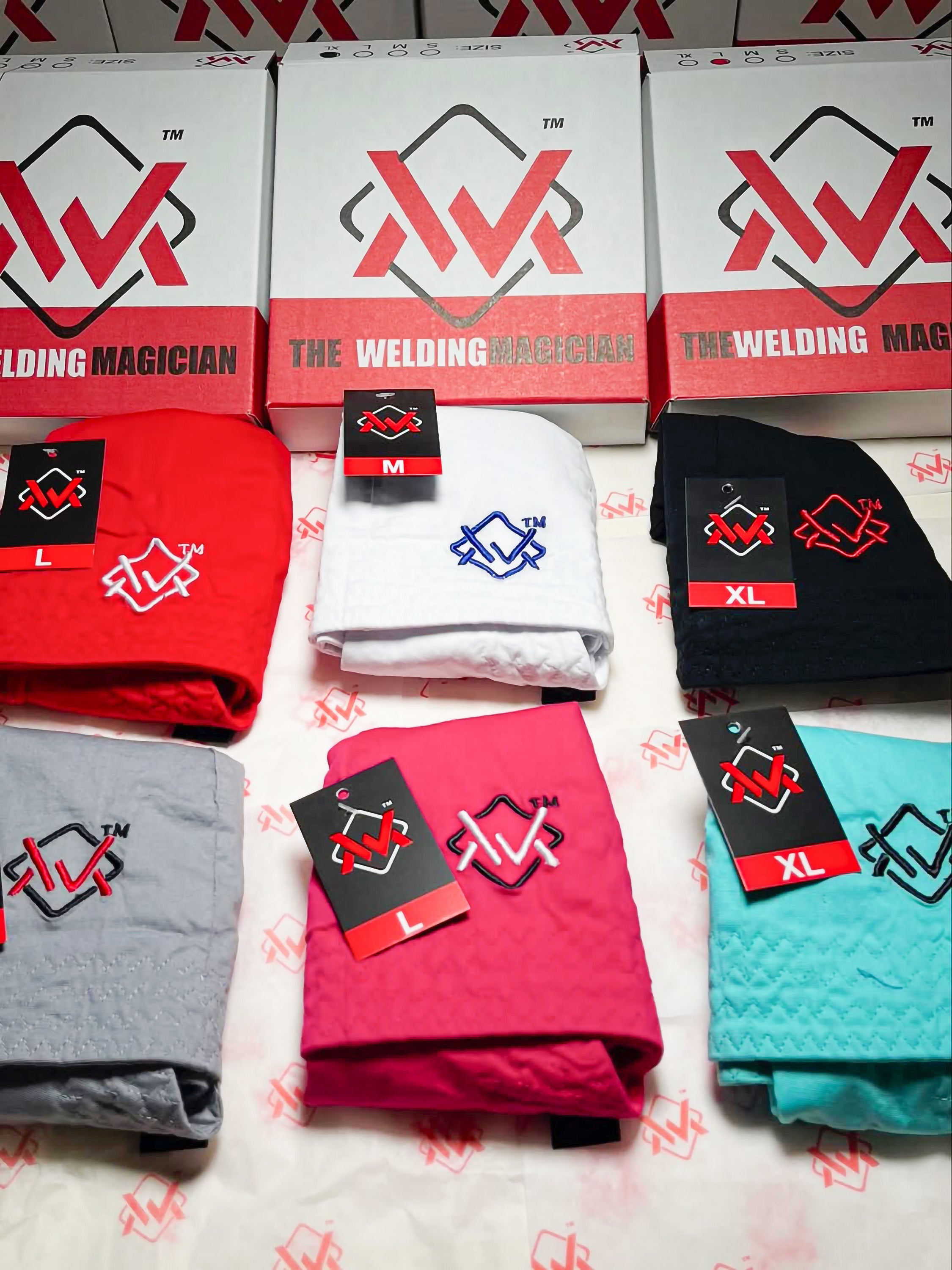 Collection of 'The Welding Magician' branded clothing and hats on a white background.