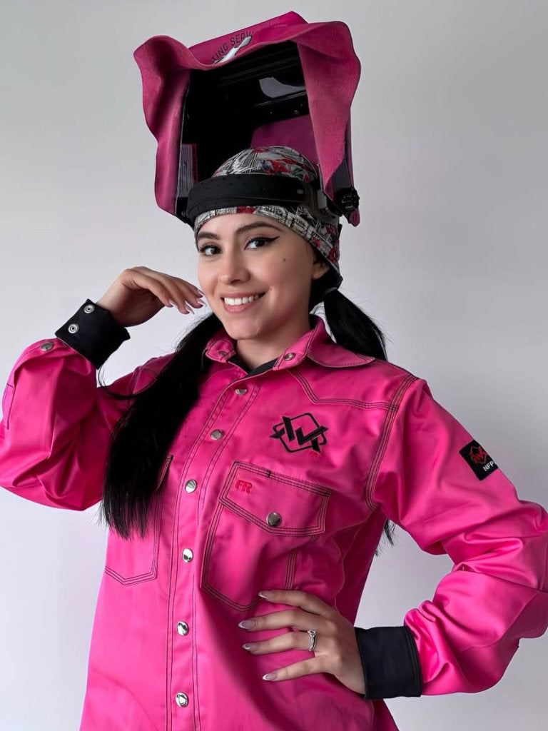 Person wearing a bright pink welding jacket and helmet on a plain background