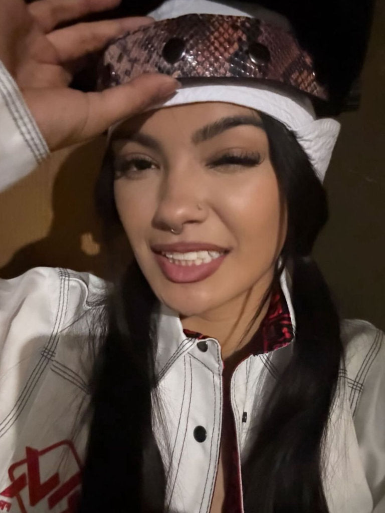 Person wearing a snake skin patterned hat and white jacket with red design.