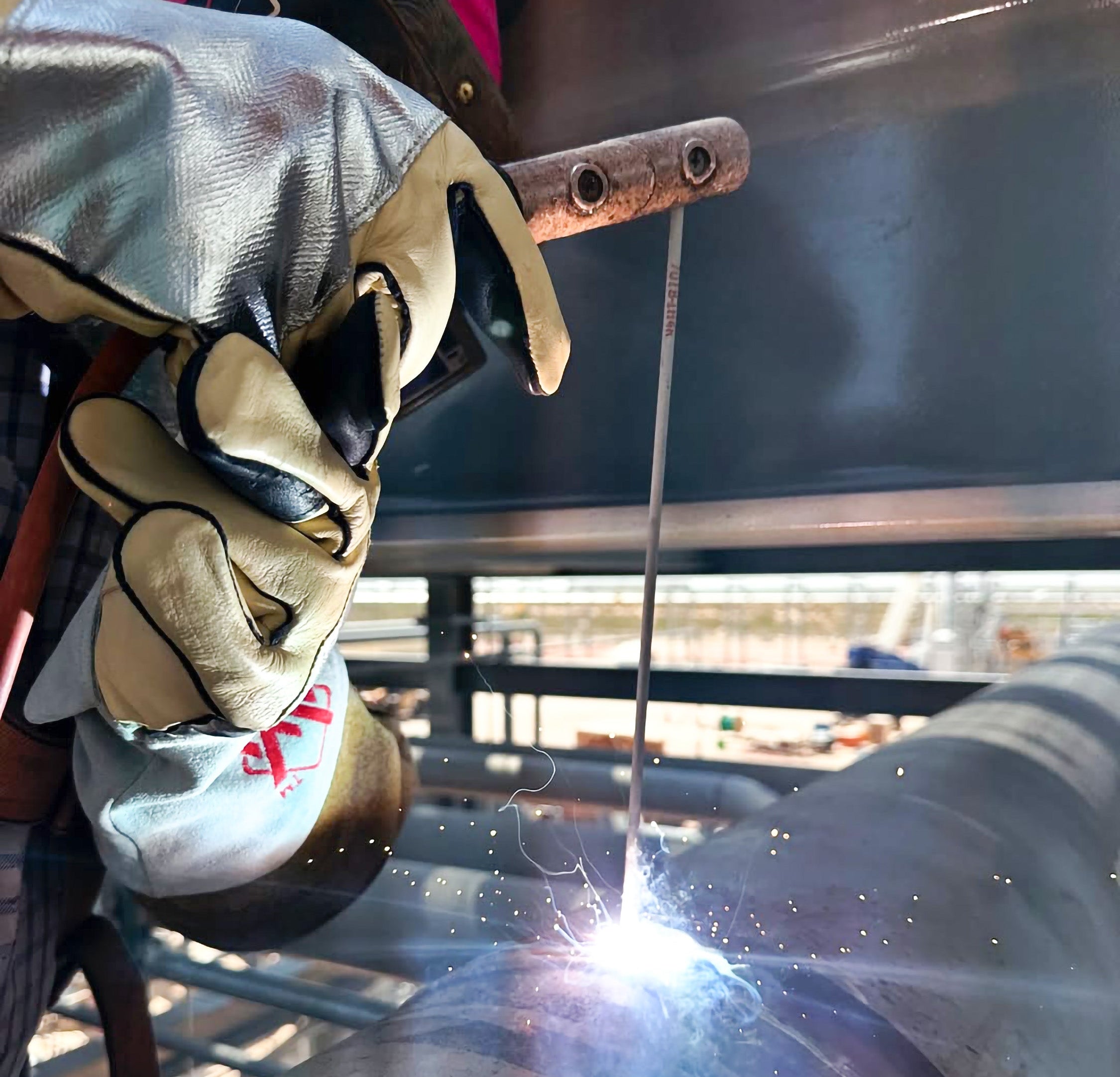 Person welding metal with protective gear in an industrial setting