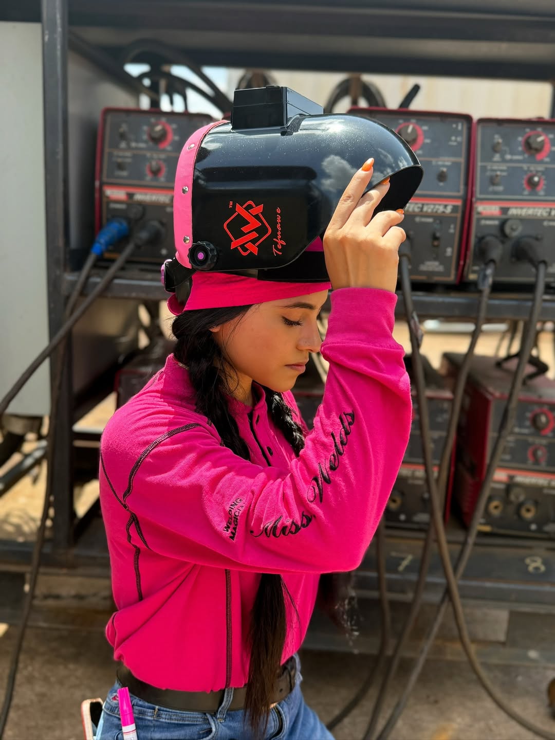 Person wearing a pink jacket and helmet in a workshop setting