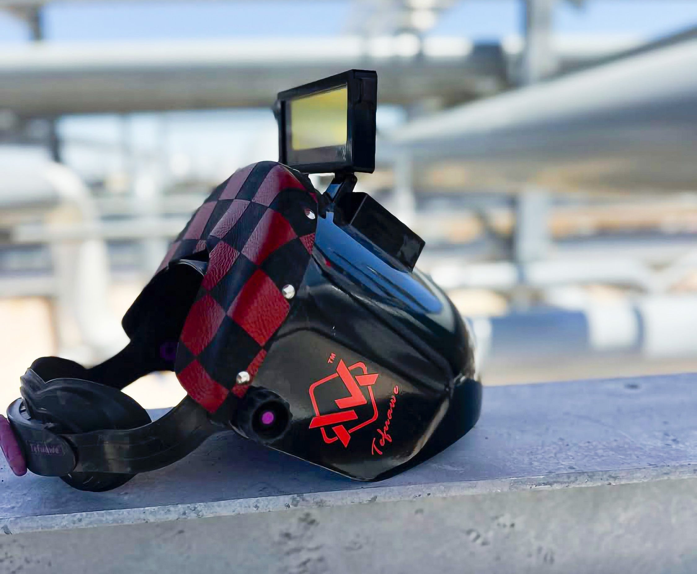 Welding helmet with checkered pattern and digital display on a blurred background