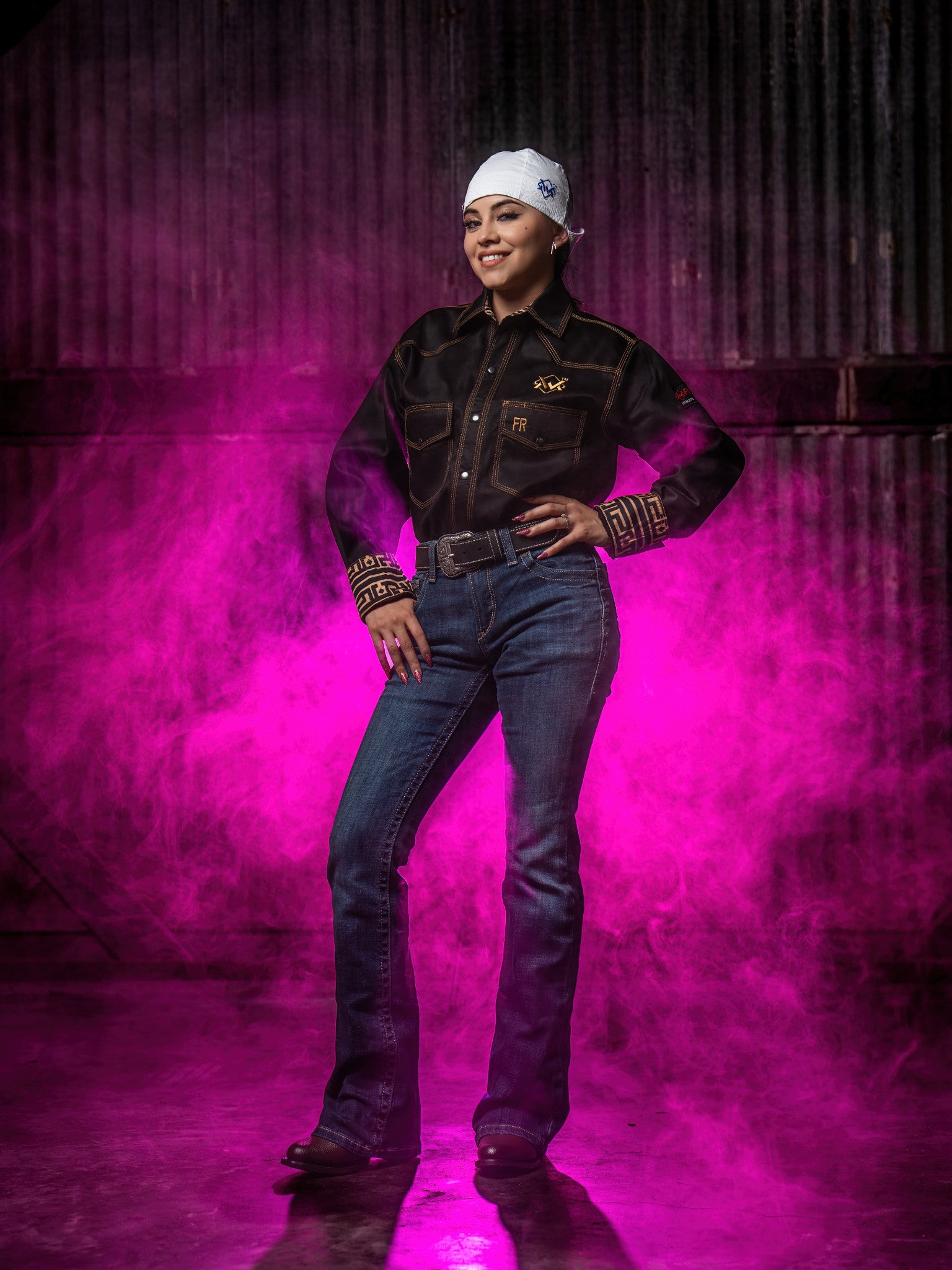 Person wearing a black shirt and jeans with a white head covering against a pink and purple gradient background