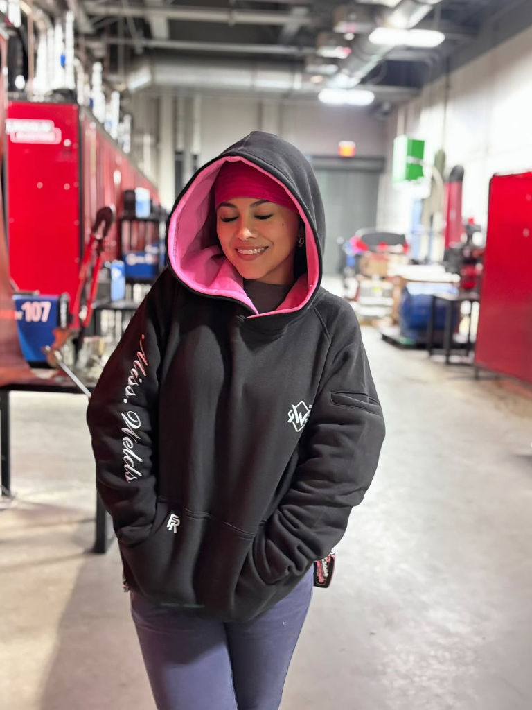 Person wearing a black hoodie with pink interior in an indoor setting