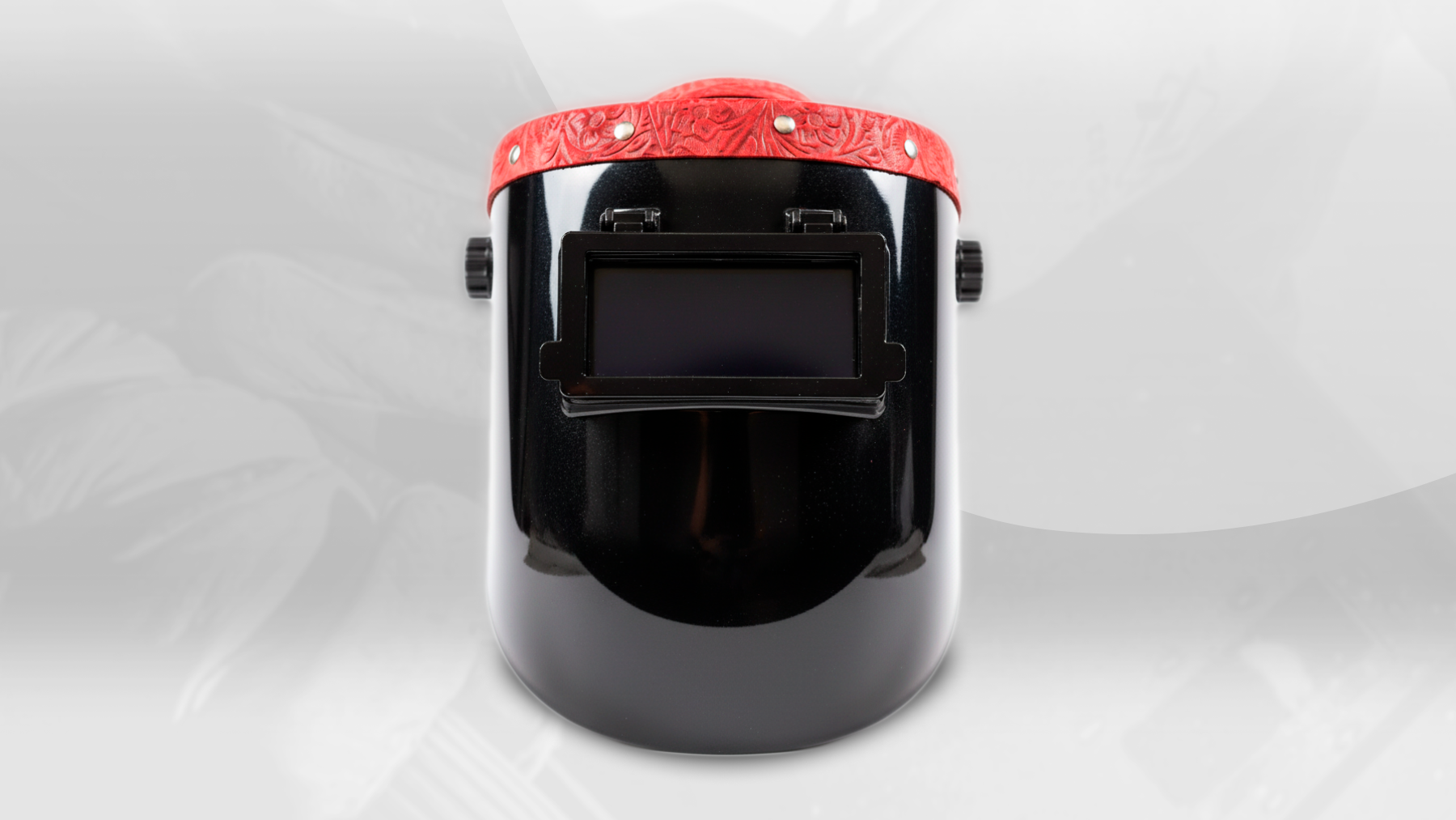 Black welding helmet with a red visor on a white background
