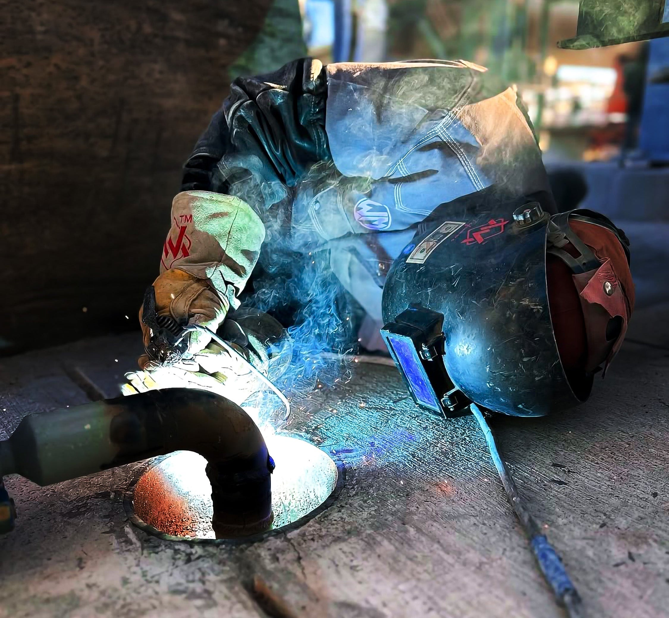 Person welding with protective gear in a workshop setting