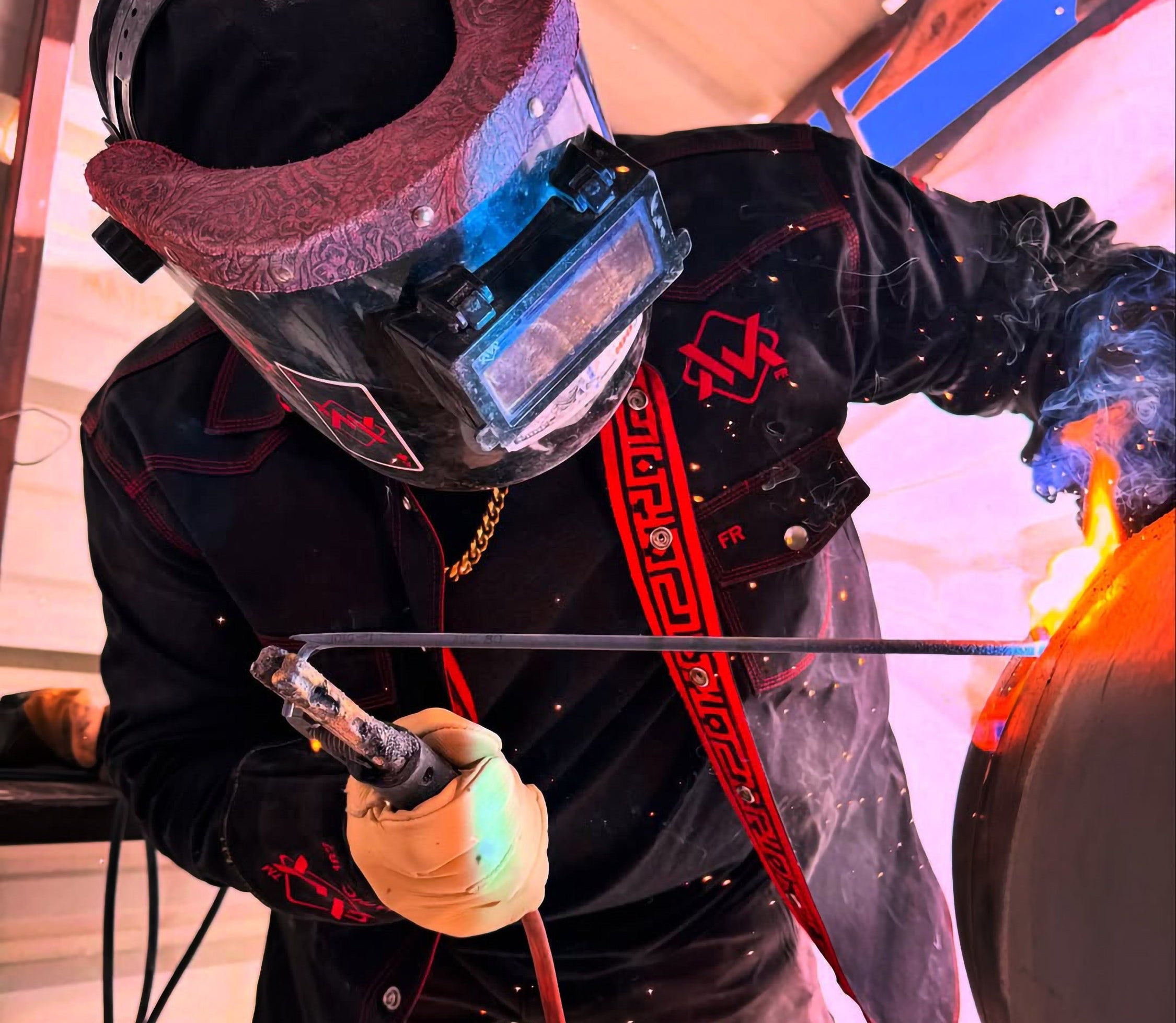 Person welding with protective gear in a workshop setting